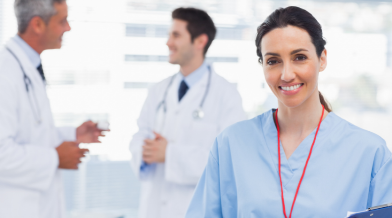Enfermeira sorrindo com médico ao fundo