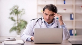 Jovem médico em frente ao computador estudando