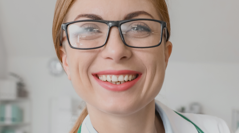 Médica com estetoscópio no pescoço sorrindo.
