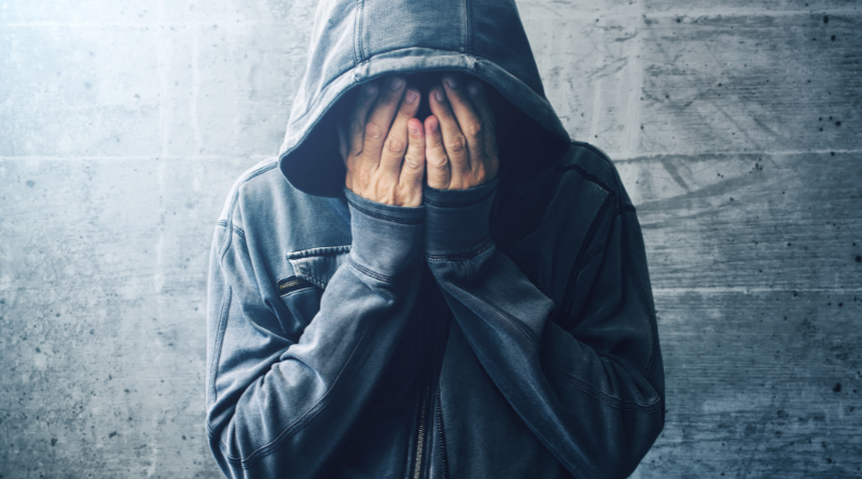 Homem tapando o rosto com as mãos