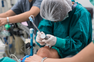 Médico realizando procedimento de intubação em paciente.