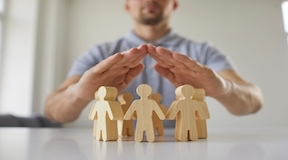 Homem com as mãos sobre figuras humanas em madeira 